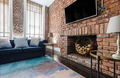 a living room with a couch and a brick wall at Luxury City Centre Apartment in Liverpool
