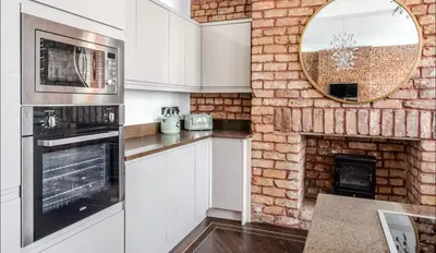 a kitchen with white cabinets and a brick fireplace at Luxury City Centre Apartment in Liverpool
