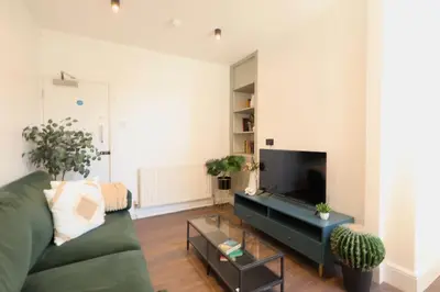 a living room with a green couch and a flat screen tv at Anfield Stadium Apartment - Perfect Matchday Stay in Liverpool