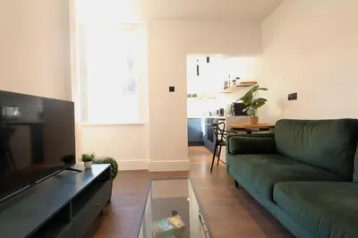 a living room with a green couch and a table at Anfield Stadium Apartment - Perfect Matchday Stay in Liverpool
