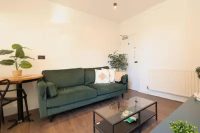 a living room with a green couch and a table at Anfield Stadium Apartment - Perfect Matchday Stay in Liverpool