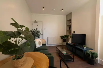 a living room with a green couch and a tv at Anfield Stadium Apartment - Perfect Matchday Stay in Liverpool