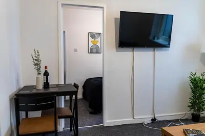 a room with a table and a television on a wall at One Bedroom Flat by Brookland Stays Serviced Accommodation Short Lets Blackpool with Free WiFi in Blackpool