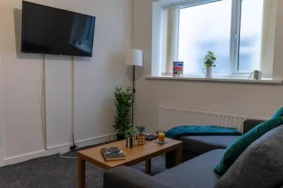 a living room with a couch and a tv on the wall at One Bedroom Flat by Brookland Stays Serviced Accommodation Short Lets Blackpool with Free WiFi in Blackpool