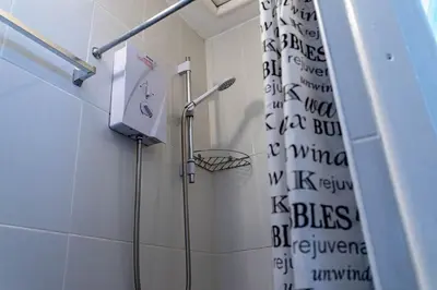 a bathroom with a shower with a shower curtain with the words bostonsteensteen at One Bedroom Flat by Brookland Stays Serviced Accommodation Short Lets Blackpool with Free WiFi in Blackpool