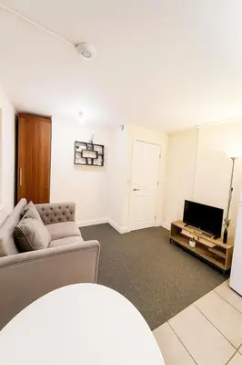 a living room with a couch and a tv at Cozy modern 2 bedroom apartment with comfortable lounge in Preston