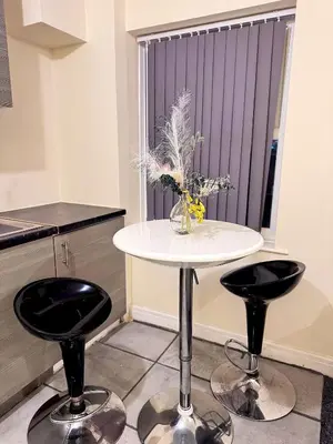 a white table with two black chairs and a vase with flowers at Cozy modern 2 bedroom apartment with comfortable lounge in Preston