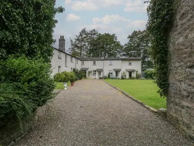 a large white house with a driveway at The Gameskeepers Cottage in Grange Over Sands