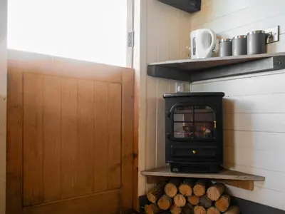 a stove in a small room with logs at Shepherds Hut - Uk50043 in Chipping