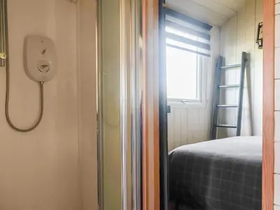 a small bedroom with a shower and a bed at Shepherds Hut - Uk50043 in Chipping