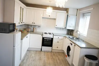 a kitchen with white cabinets and a washer and dryer at The Townhouse Liverpool in Liverpool