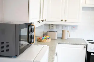 a kitchen with white cabinets and a microwave at The Townhouse Liverpool in Liverpool