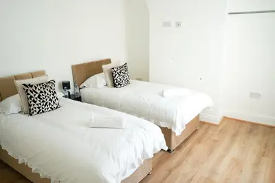 two beds in a room with white walls and wooden floors at The Butterfield in Liverpool