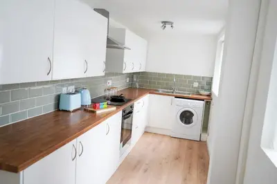 a kitchen with white cabinets and a washer and dryer at The Butterfield in Liverpool