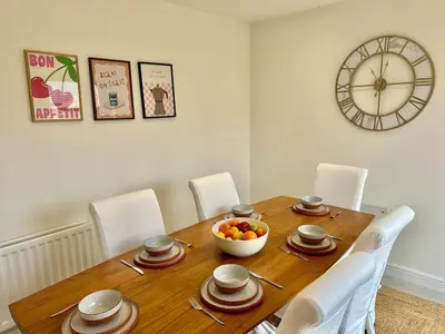 a dining room table with a bowl of fruit and a clock at The Nest at Heaton Family Friendly Near Preston and Blackpool Ample Parking and WiFi in Kirkham