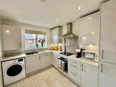 a kitchen with white cabinets and a washer and dryer at The Nest at Heaton Family Friendly Near Preston and Blackpool Ample Parking and WiFi in Kirkham