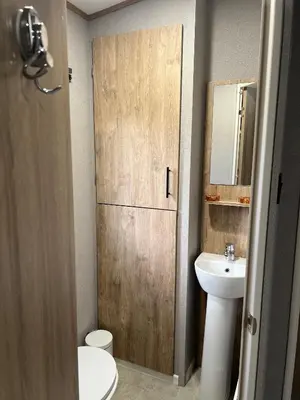 a bathroom with a sink and a toilet and a door at Modern Caravan 2025 with Decking in Morecambe