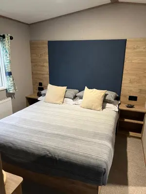 a bedroom with a large bed with a blue headboard at Modern Caravan 2025 with Decking in Morecambe