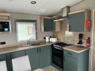 a kitchen with green cabinets and a stove top oven at Modern Caravan 2025 with Decking in Morecambe
