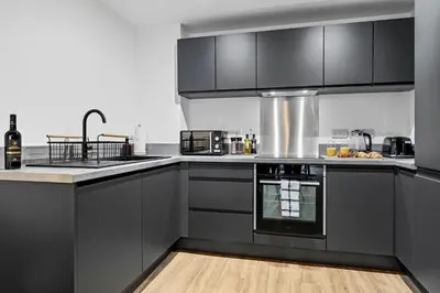 a kitchen with black cabinets and a counter top at 2BR Apt - City Centre - Parking - Balcony - Long Stays - Contractors in Liverpool