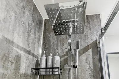a bathroom with a shower with four bottles of soap at 2BR Apt - City Centre - Parking - Balcony - Long Stays - Contractors in Liverpool