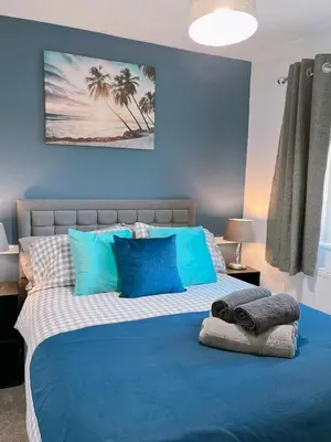 a blue bedroom with a large bed with blue pillows at Modern 3-bed house with parking - Chorley Near M61 in Heapey