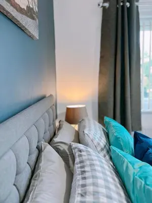 a bed with pillows sitting next to a window at Modern 3-bed house with parking - Chorley Near M61 in Heapey