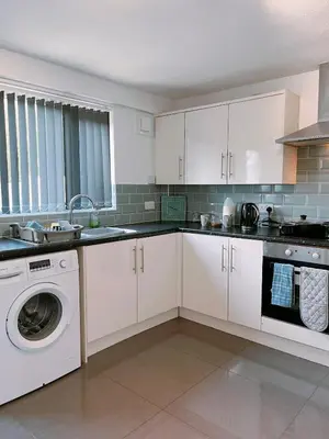 a kitchen with white cabinets and a washing machine at Modern 3-bed house with parking - Chorley Near M61 in Heapey