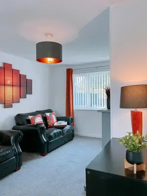 a living room with a black leather couch and a table at Modern 3-bed house with parking - Chorley Near M61 in Heapey