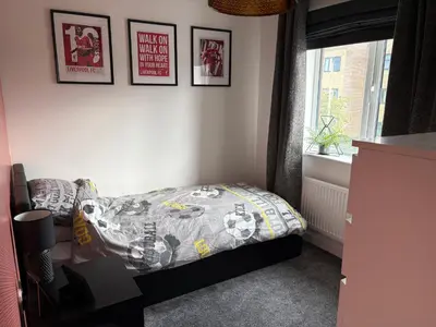 a bedroom with a bed and some pictures on the wall at Modern Detached House with multiple parking and large garden next to Anfield Stadium in Liverpool