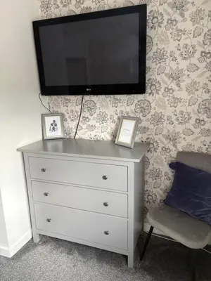 a dresser with a flat screen tv on a wall at Modern Detached House with multiple parking and large garden next to Anfield Stadium in Liverpool