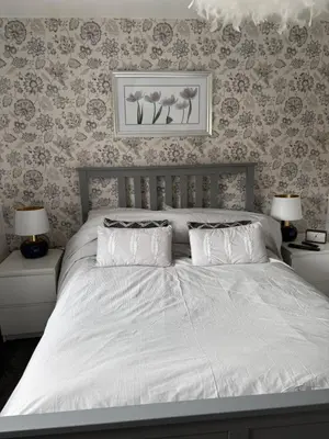 a bed with white sheets and pillows in a bedroom at Modern Detached House with multiple parking and large garden next to Anfield Stadium in Liverpool