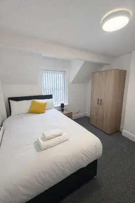 a bedroom with a large white bed and a wooden cabinet at The Big Home - 8 bedrooms, 11 Beds, Long stays welcome, Free parking in Wallasey