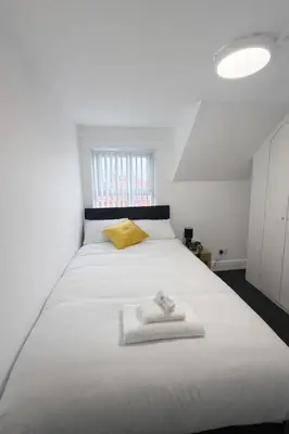 a bedroom with a large white bed with a yellow pillow at The Big Home - 8 bedrooms, 11 Beds, Long stays welcome, Free parking in Wallasey