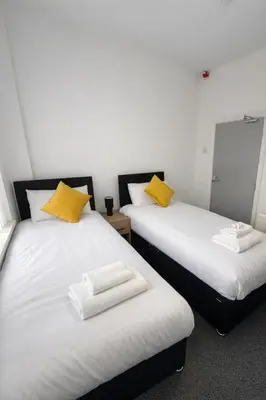 two beds with yellow pillows in a room at The Big Home - 8 bedrooms, 11 Beds, Long stays welcome, Free parking in Wallasey