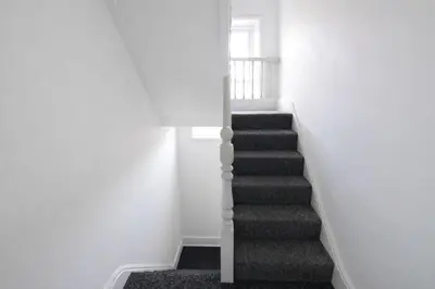 a staircase in a white room with white walls at The Big Home - 8 bedrooms, 11 Beds, Long stays welcome, Free parking in Wallasey