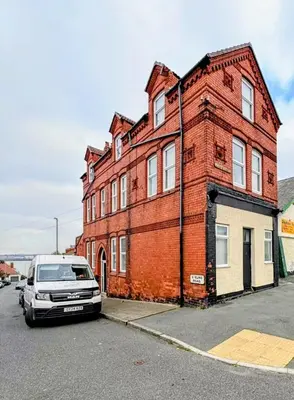 a red brick building with a van parked in front of it at The Big Home - 8 bedrooms, 11 Beds, Long stays welcome, Free parking in Wallasey