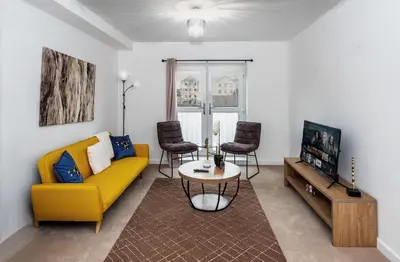 a living room with a yellow couch and a tv at Modern Downtown Gem- Brand New Apartments on Cannon St in Preston