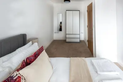 a bedroom with a white bed and a hallway at Modern Downtown Gem- Brand New Apartments on Cannon St in Preston