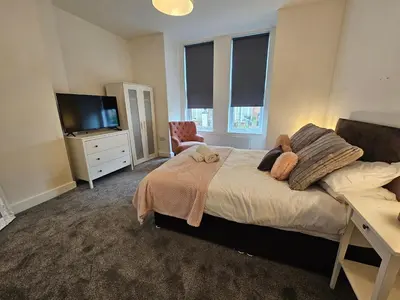 a bedroom with a bed with a television and a desk at Kings Central 3 Bedroom, free parking & Wifi, dog friendly in Southport