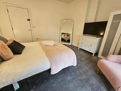 a bedroom with a bed and a flat screen tv at Kings Central 3 Bedroom, free parking & Wifi, dog friendly in Southport