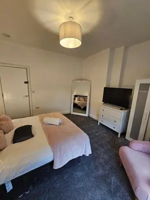 a bedroom with two beds and a television in it at Kings Central 3 Bedroom, free parking & Wifi, dog friendly in Southport