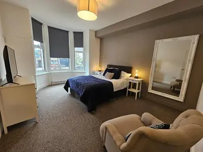 a bedroom with a bed and a mirror and a couch at Kings Central 3 Bedroom, free parking & Wifi, dog friendly in Southport
