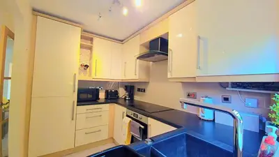 a kitchen with white cabinets and a sink at Modern luxury 3-bedroom guesthouse in Wigan in Wigan