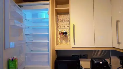 an empty refrigerator with its door open in a kitchen at Modern luxury 3-bedroom guesthouse in Wigan in Wigan