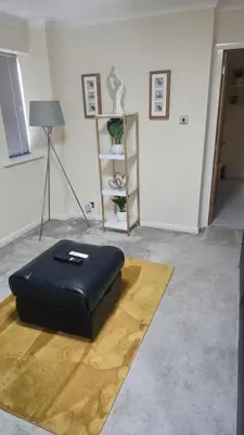 a black ottoman sitting on the floor in a room at Modern luxury 3-bedroom guesthouse in Wigan in Wigan
