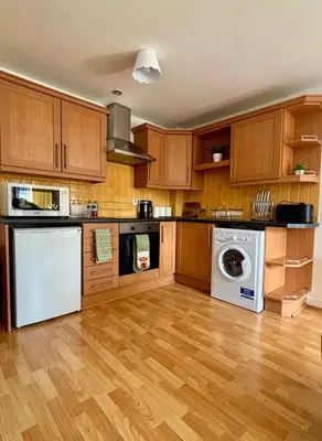 a kitchen with wooden cabinets and a washer and dryer at Stylish City Centre Stay - 4 mins to station - Fast Wifi - Near Stadiums in Liverpool