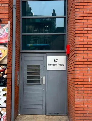 a door in a brick building with a london road sign at Stylish City Centre Stay - 4 mins to station - Fast Wifi - Near Stadiums in Liverpool