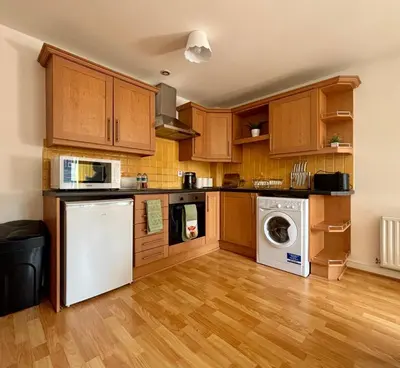a kitchen with wooden cabinets and a washer and dryer at Stylish City Centre Stay - 4 mins to station - Fast Wifi - Near Stadiums in Liverpool