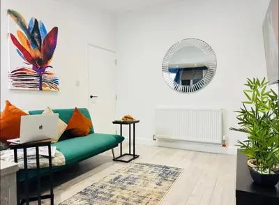 a living room with a green couch and a laptop at The Anfield Snug Terraced, 3 Bedroom Home with Ensuite & Free On-Street Parking in Liverpool